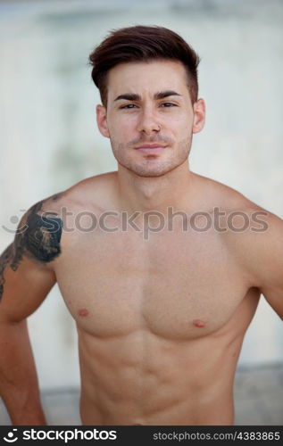 Handsome fit athletic shirtless young man with a tattoo