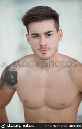 Handsome fit athletic shirtless young man with a tattoo