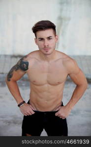 Handsome fit athletic shirtless young man with a tattoo