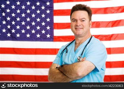 Handsome friendly doctor standing with arms crossed in front of American flag. Photographed in front of flag, not a composite image.