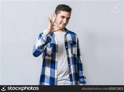 Handsome guy gesturing everything is ok, Person making ok gesture isolated, Smiling man showing ok gesture looking at camera, Concept of expression of everything is fine.