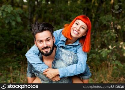 Handsome guy giving piggyback ride to girlfriend in a park