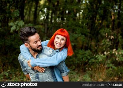 Handsome guy giving piggyback ride to girlfriend in a park