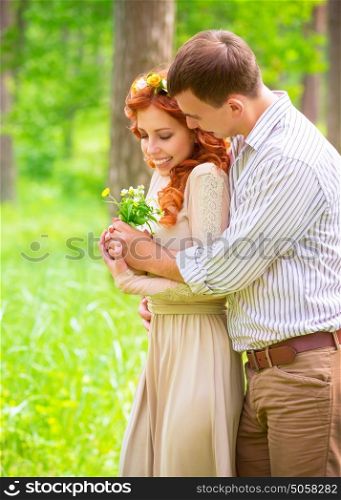 Handsome guy giving to her precious girlfriend bouquet of wildflower, spending date in the park, enjoying romantic relationship