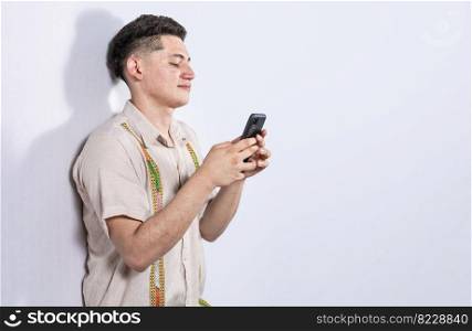 Handsome guy happy with his cell phone on isolated backgrounds, young latin man happy with his cell phone isolated, man on white background texting with his cell phone