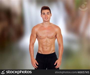 Handsome guy in bathing suit with an unfocused waterfall background
