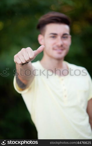 Handsome guy in the park with yellow t-shirt saying Ok