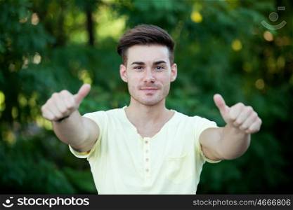 Handsome guy in the park with yellow t-shirt saying Ok