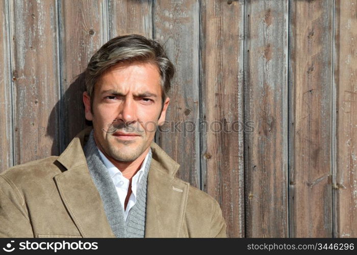 Handsome guy standing against wooden house