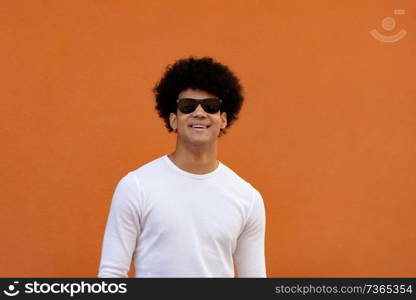 Handsome guy wiht sunglasses and a orange wall of background