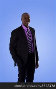 Handsome happy African American corporate business man smiling, wearing black suit with purple shirt, standing with hand in pocket, isolated.