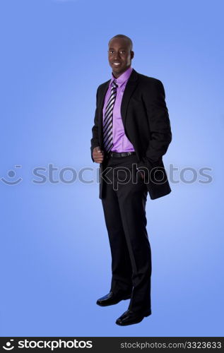 Handsome happy African American corporate business man smiling, wearing black suit with purple shirt, standing with authority with hand in pocket, isolated.