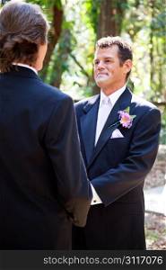 Handsome hispanic groom marrying his same sex partner in an outdoor wedding ceremony.
