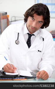 Handsome hospital doctor writing in a personal organizer