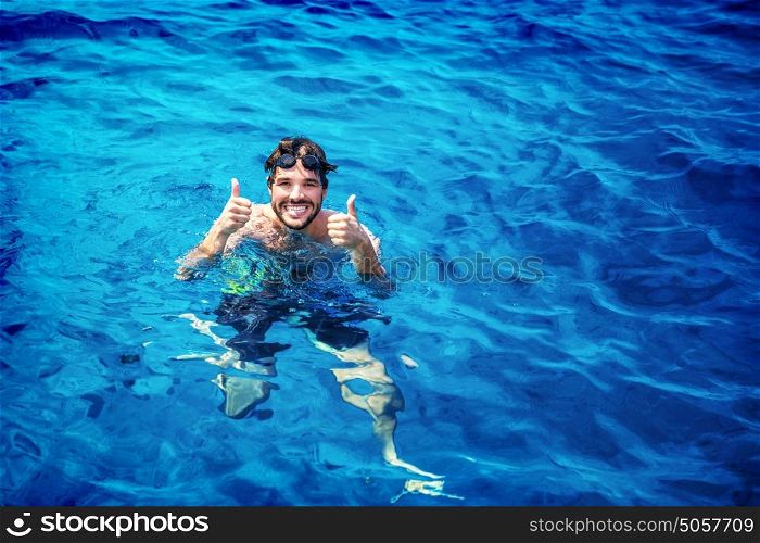Handsome instructor of swimming wearing goggles in the pool, having fun in the water, summer adventure, travel and vacation concept