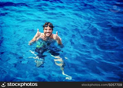 Handsome instructor of swimming wearing goggles in the pool, having fun in the water, summer adventure, travel and vacation concept