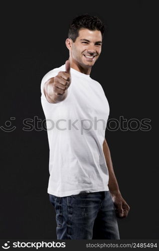 Handsome latin man with thumbs up, isolated over a dark background