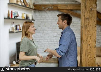 Handsome loving young boyfriend smiling while holding hands of girlfriend in a loft apartment