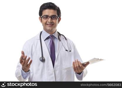 Handsome male doctor holding clipboard gesturing on white background