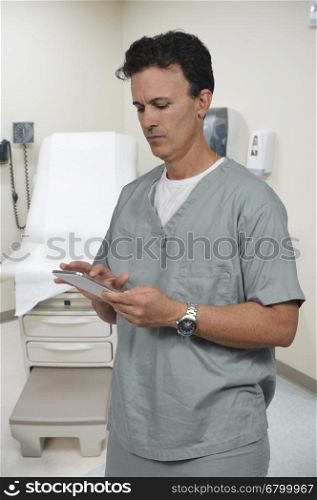 Handsome male doctor in scrubs using a tablet