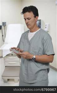 Handsome male doctor in scrubs using a tablet