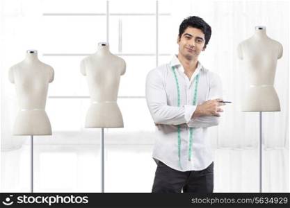 Handsome male fashion designer standing by mannequin at studio