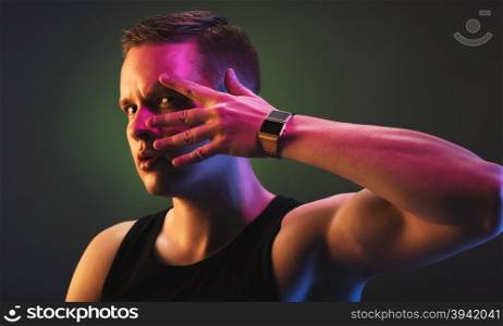 Handsome male model posing for camera wearing tank top and wrist watch.