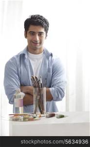 Handsome male painter with arms crossed in art studio