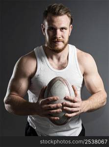 handsome male rugby player holding ball