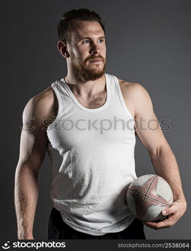 handsome male rugby player holding ball hip