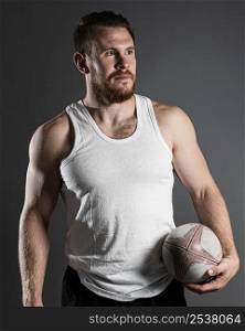 handsome male rugby player holding ball hip