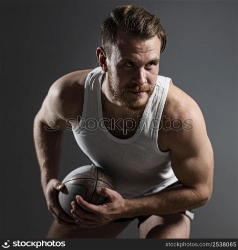 handsome male rugby player holding ball posing