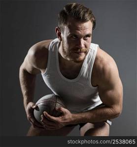 handsome male rugby player holding ball posing