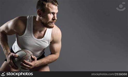 handsome male rugby player holding ball with copy space