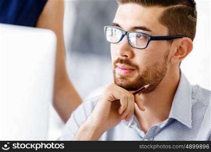 Handsome male worker in office. Handsome businessman in office in front of computer