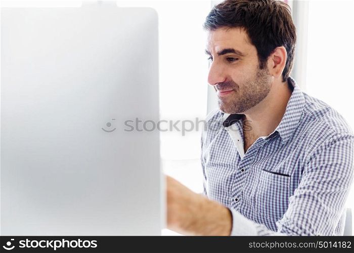 Handsome male worker in office. Handsome young businessman in office sitting at desk