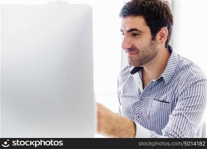 Handsome male worker in office. Handsome young businessman in office sitting at desk