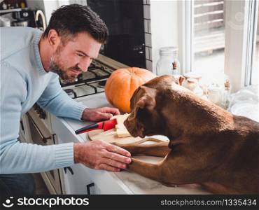 Handsome man and an adorable, pretty puppy. Close-up, indoor. Day light, studio photo. Concept of care, education, obedience training and raising pets. Handsome man and an adorable, pretty puppy
