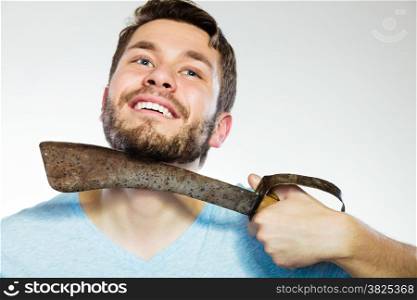 Handsome man bearded guy shaving with very large knife on gray background. Humour