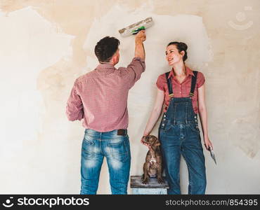 Handsome man, beautiful woman and young, charming puppy, repairing their cozy home. Close-up, white isolated background. Studio photo. Concept of care, education, training and raising of animals. Handsome man, beautiful woman and charming puppy,