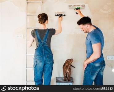 Handsome man, beautiful woman and young, charming puppy, repairing their cozy home. Close-up, white isolated background. Studio photo. Concept of care, education, training and raising of animals. Handsome man, beautiful woman and charming puppy,