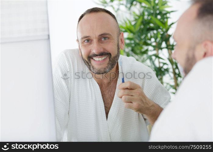handsome man brushing teeth in bathroom