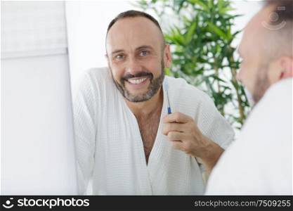 handsome man brushing teeth in bathroom