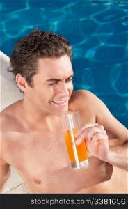 Handsome man by the poolside with a glass of orange juice