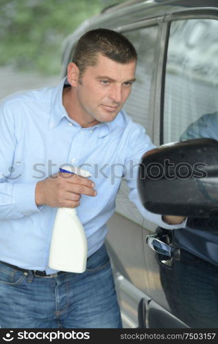 handsome man cleaning a car by hand