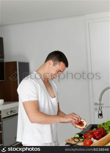 Handsome man cooking at home preparing salad in kitchen.