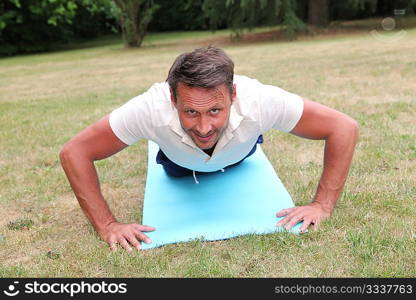 Handsome man doing fitness exercises outside