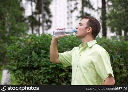 Handsome man drinking water in summer park