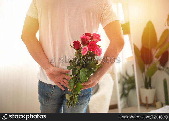 Handsome man hide bunch of roses in hand before give to his girlfriend,valentine day or celebration or congratulation concept.