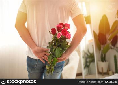 Handsome man hide bunch of roses in hand before give to his girlfriend,valentine day or celebration or congratulation concept.